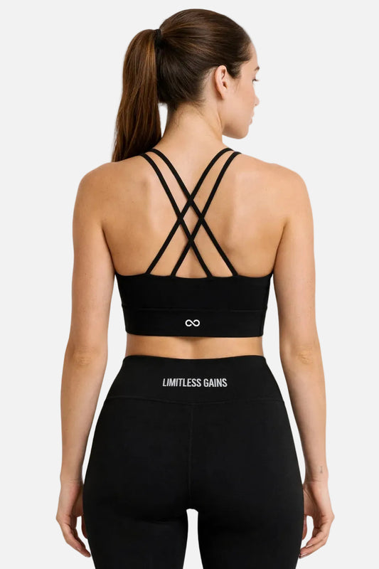 Woman wearing a black sports bra and leggings with 'Limitless Gains' branding on a white background