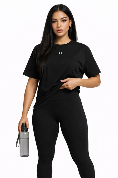 Woman wearing a black athletic outfit holding a water bottle on a white background