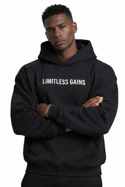 Man wearing a black hoodie with 'LIMITLESS GAINS' text on a white background