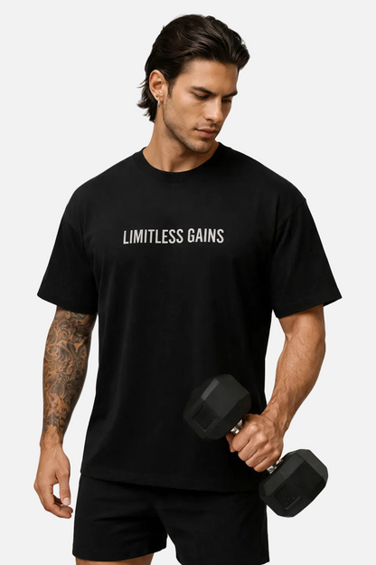 Man wearing a black t-shirt with 'Limitless Gains' text, holding a dumbbell on a white background