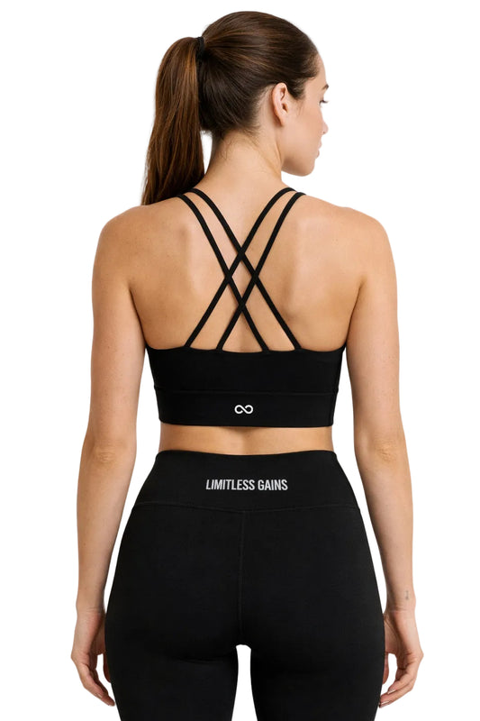 Woman wearing a black sports bra and leggings with 'Limitless Gains' branding on a white background
