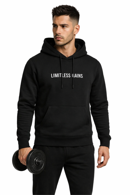 Man wearing a black hoodie with 'Limitless Gains' text, holding a dumbbell on a white background
