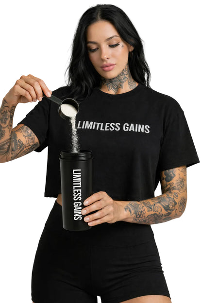 Person wearing a 'Limitless Gains' t-shirt and pouring powder into a shaker.