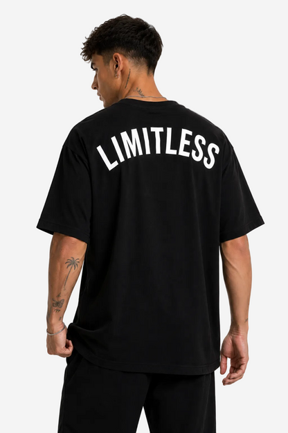 A man wearing a black oversized t-shirt with 'LIMITLESS' printed in white arched text across the back, shown from behind against a plain white background.