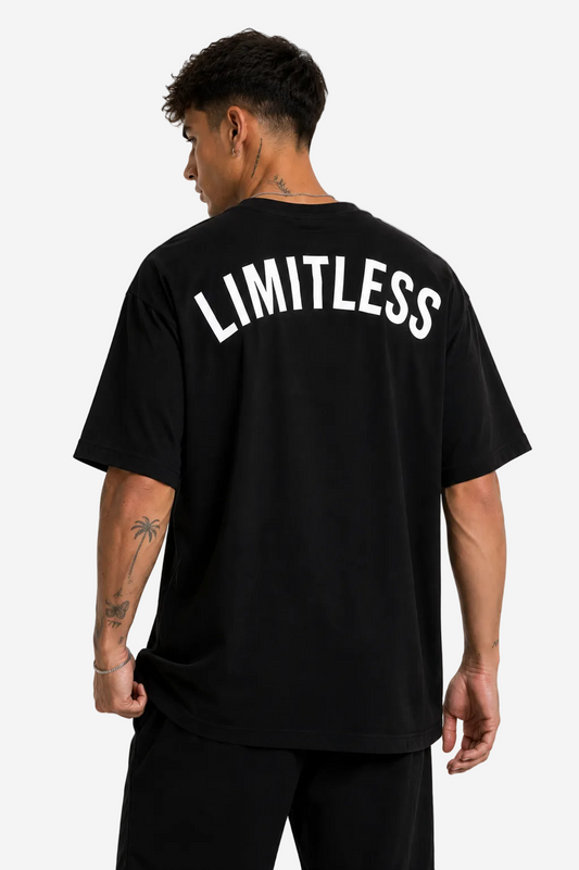 A man wearing a black oversized t-shirt with 'LIMITLESS' printed in white arched text across the back, shown from behind against a plain white background.