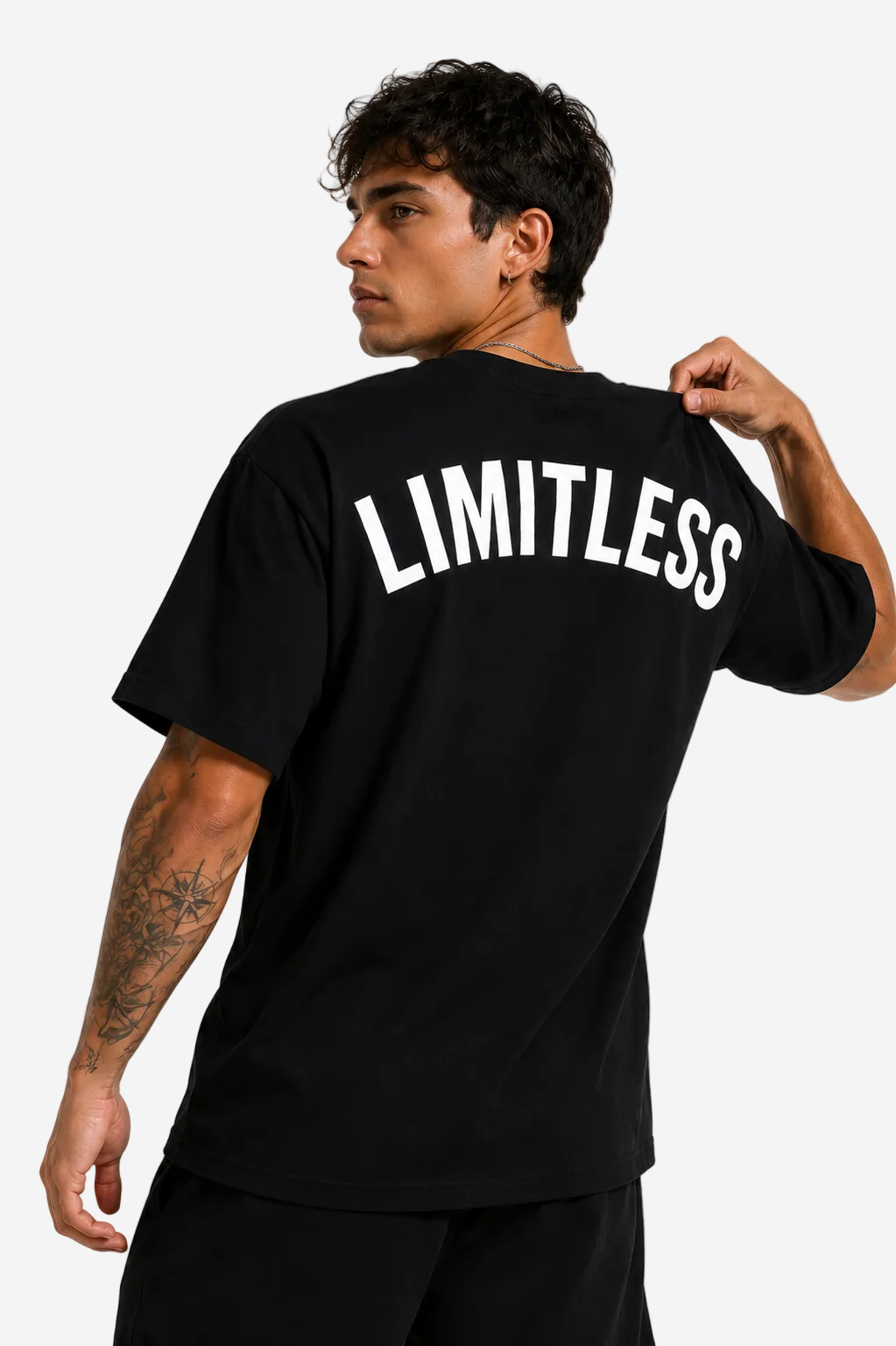 A man wearing a black t-shirt with the word 'LIMITLESS' printed in bold white letters across the back, shown from a three-quarters back view against a light gray studio background.