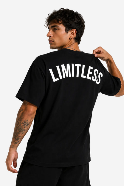 A man wearing a black t-shirt with the word 'LIMITLESS' printed in bold white letters across the back, shown from a three-quarters back view against a light gray studio background.