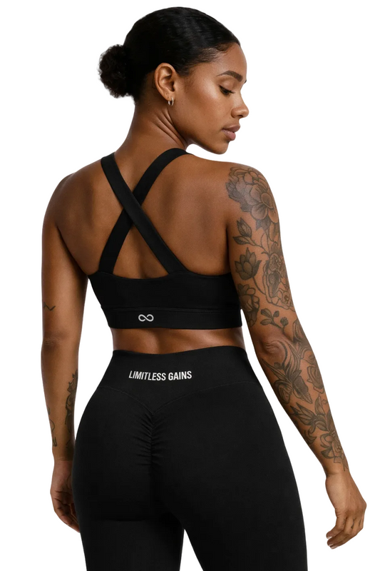 Woman wearing a black sports bra and leggings with 'Limitless Gains' branding on a white background