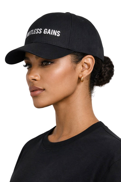 Woman wearing a black cap with 'Limitless Gains' text on a white background