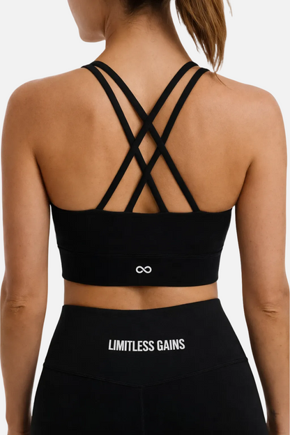 Black sports bra with criss-cross back design and 'Limitless Gains' text on leggings.